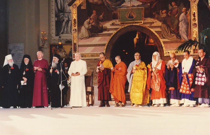 Juan Pablo II presidiendo el primer encuentro de Asís en 1986. Se encuentra dentro de la Basílica de Santa María de los Ángeles, rodeado de los representantes de las "religiones"